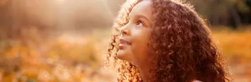 Afro american happiness little girl with curly hair receives miracle sun rays from the sky