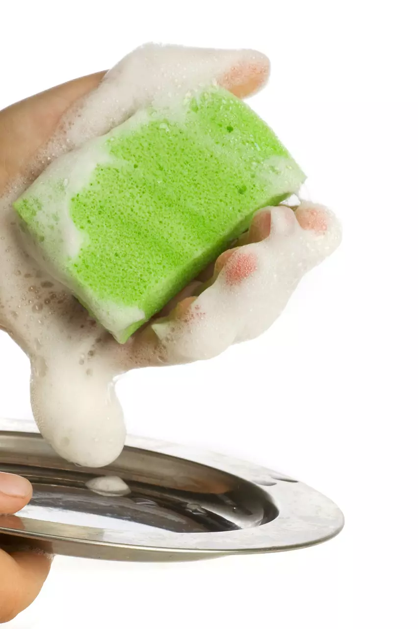 Hand washing plate with a green sponge with a lot of suds on a white background