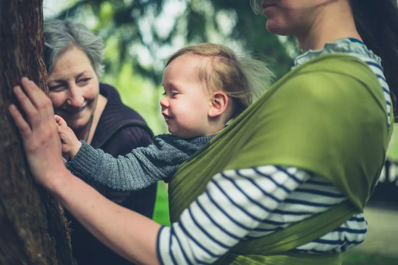 Women and baby on hike touching a tree