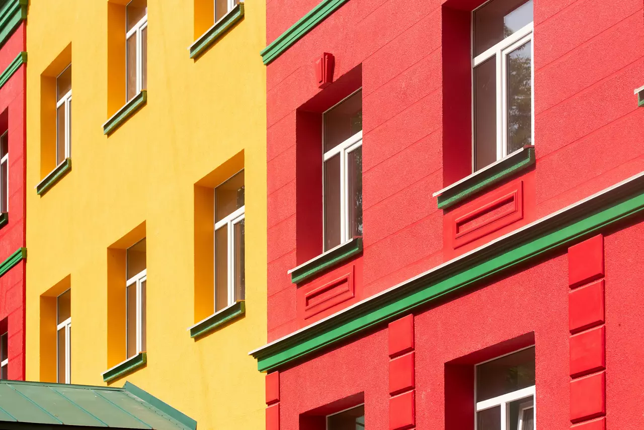 Row of brightly colored buildings in red and yellow with green cornice, building element