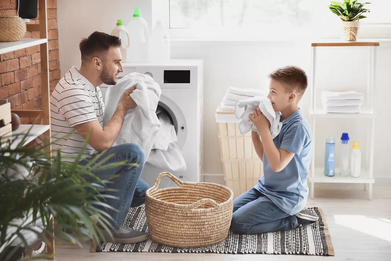Man and his little son doing laundry at home