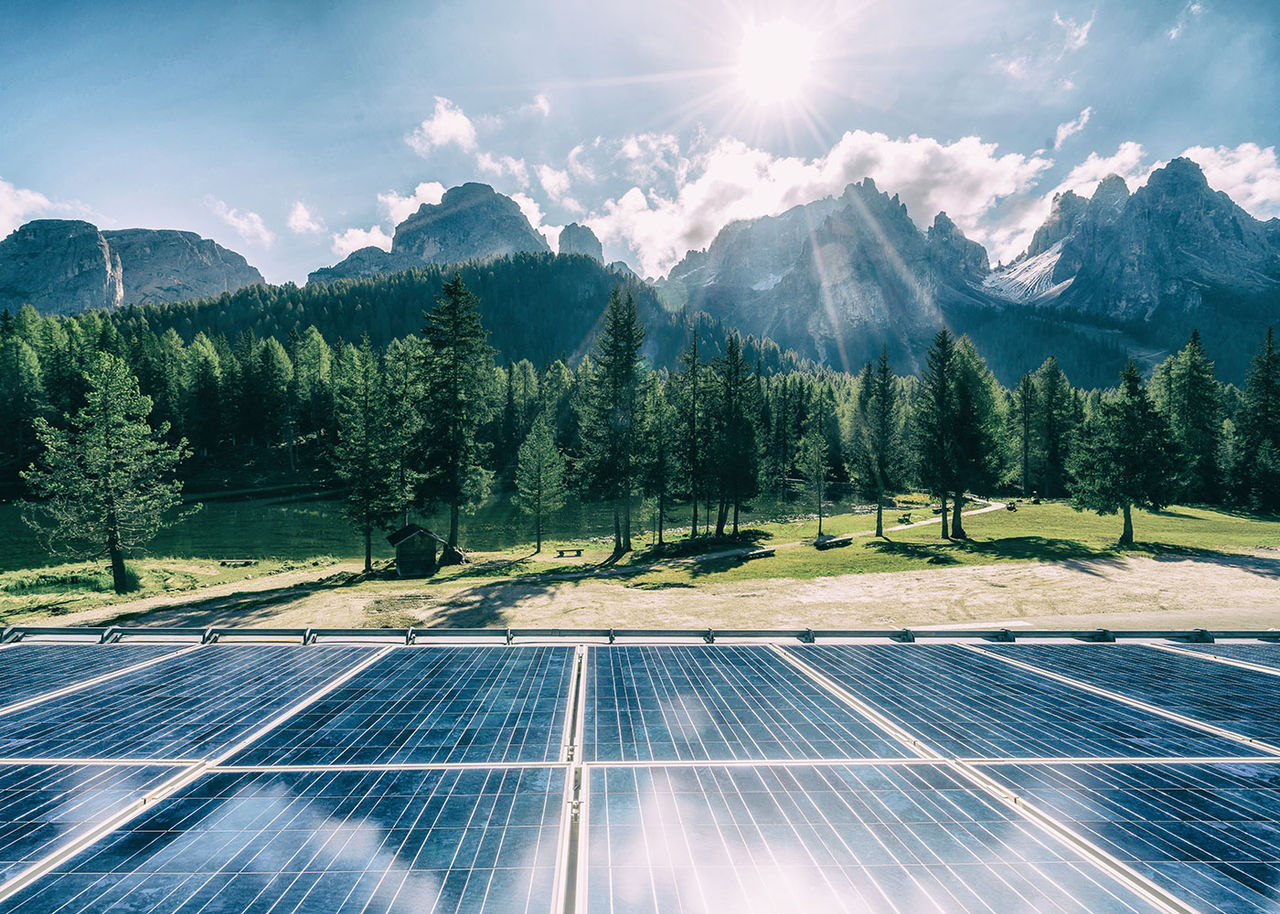 solar panels with mountains and sun in the background