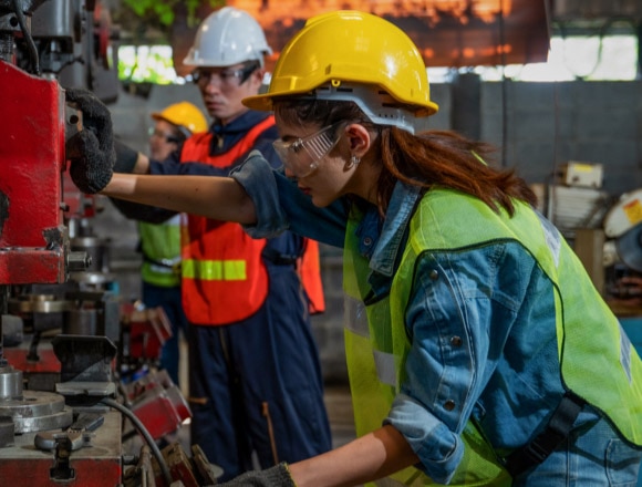 Woman uses a piece of machinery in a factory