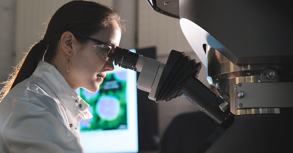scientist in lab looking in a microscope