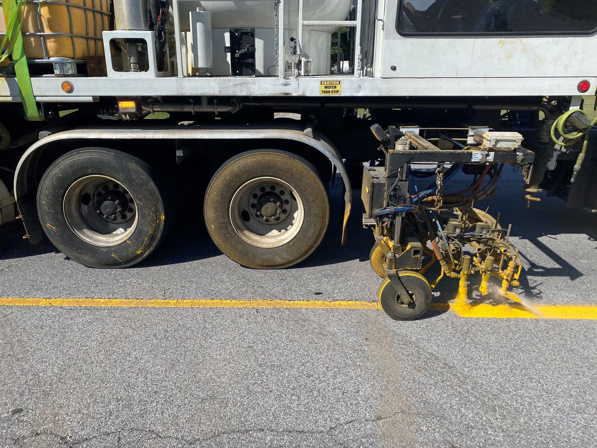 Close up of pavement marking vehicle applying paint to highway