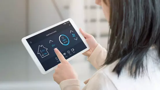 Woman control temperature in living room with smart home control app on tablet. View from the shoulder. Tehnology automation concept.