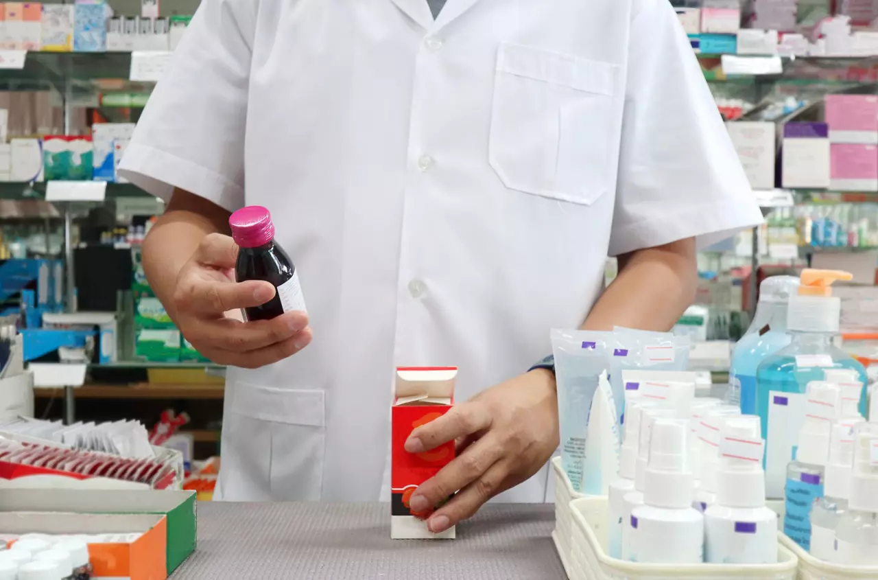 An Asian male pharmacist examining a liquid cough syrup in pharmacy