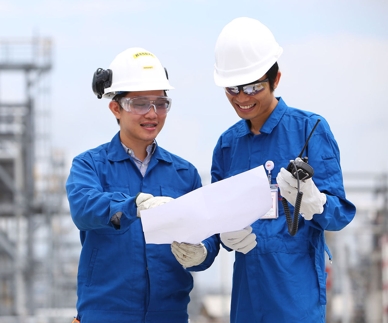 Two colleagues in a plant look at a piece of paper
